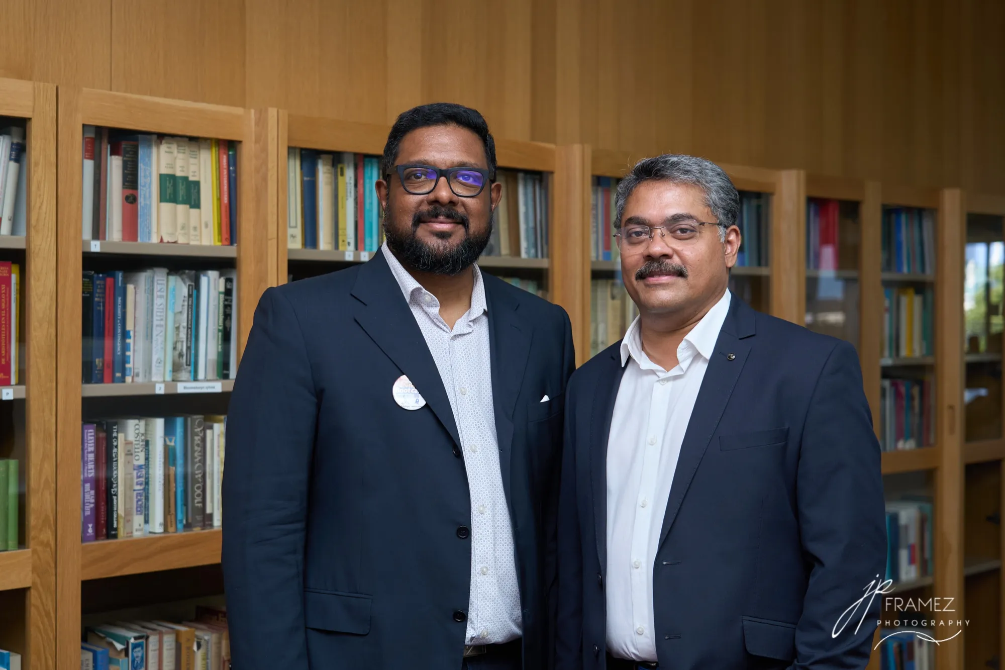 The two co-founders of VentureVillage standing side by side in front of wooden bookshelves.