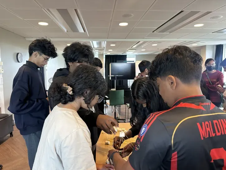 Students building a structure together around a table.