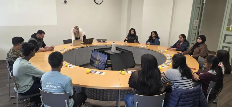 Students in a workshop around a round table with a facilitator.