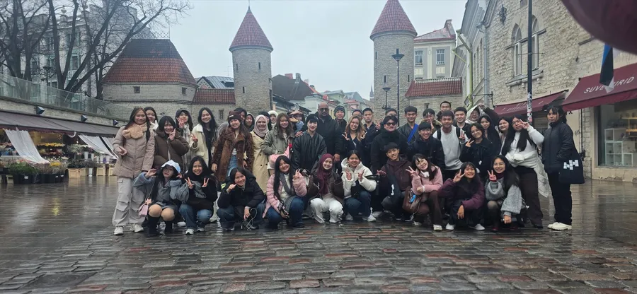 A student group in front of the Viru Gate towers in Tallinn Old Town on a rainy day.